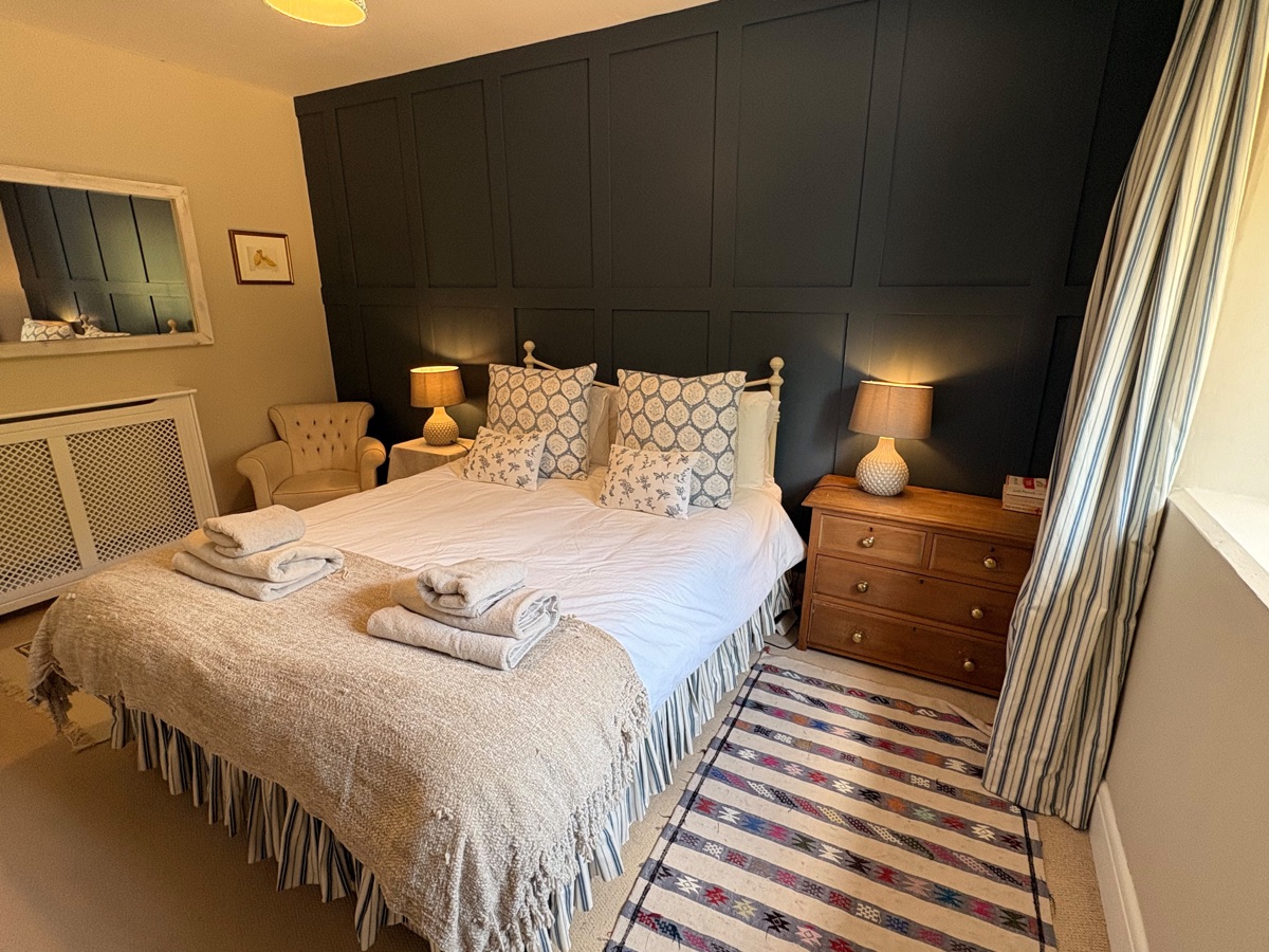 Main bedroom with king-size bed, feature wall and towels